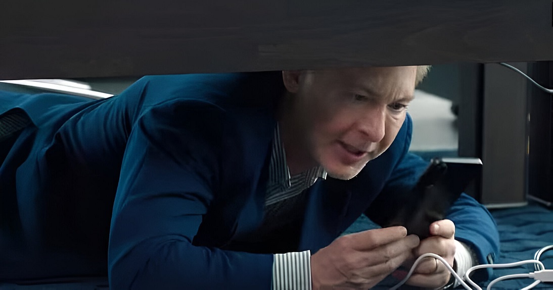 Adrian Suar esta escondido debajo de su escritorio mirando su movil